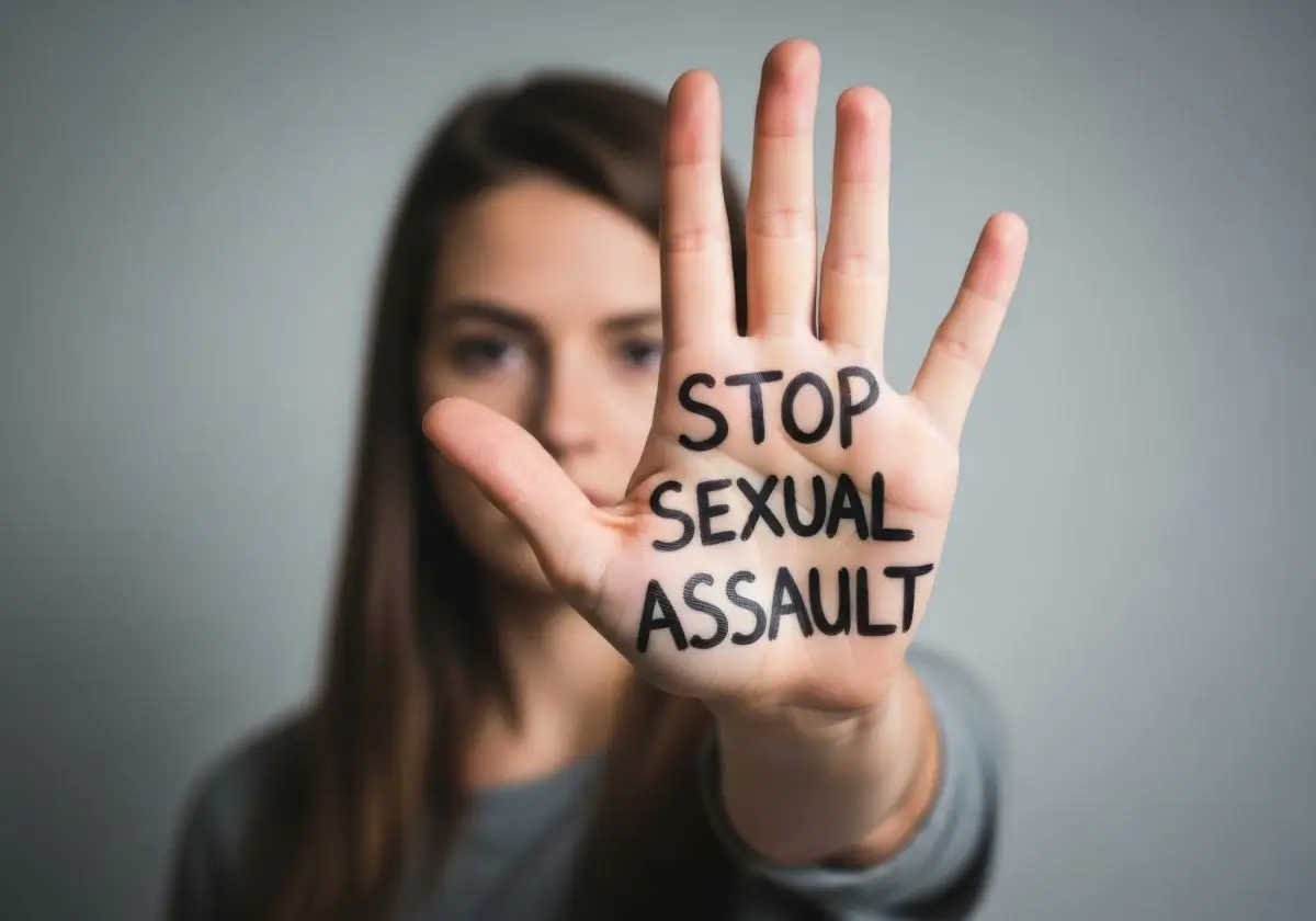 Woman holding up her hand with ‘STOP SEXUAL ASSAULT’ written on her palm, symbolizing California employees standing up for survivor rights and protections at work.
