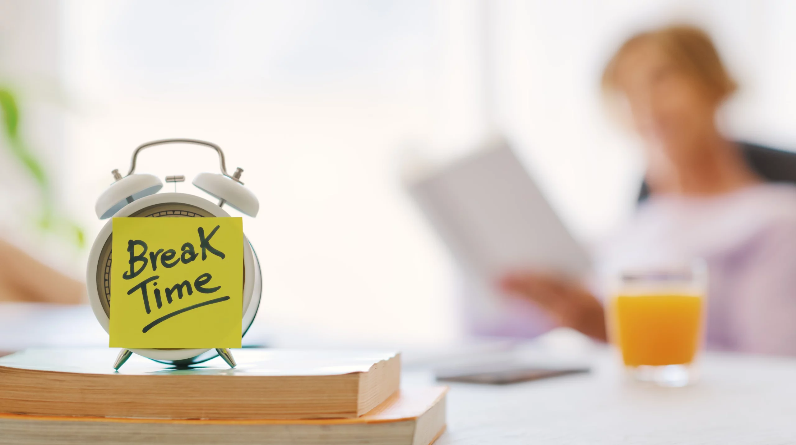 Alarm clock placed on top of books with break time notes, representing employee rights to rest breaks and scheduled work pauses in the workplace.